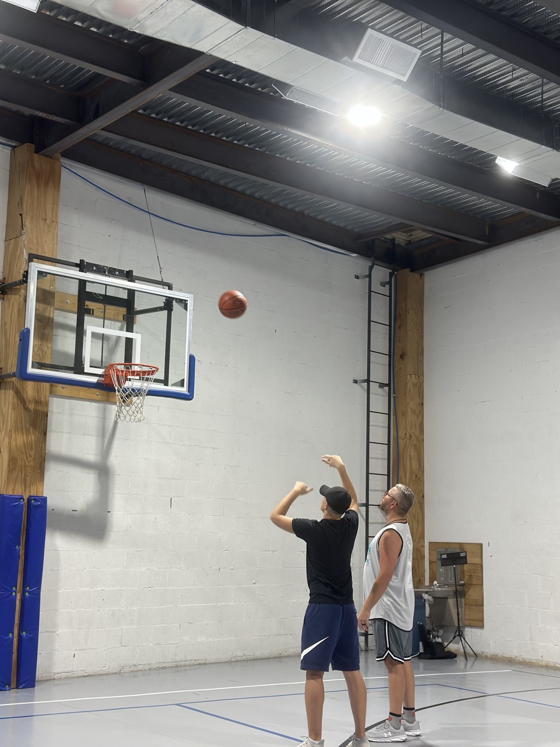 A basketball coach guiding a player through a shot at the hoop.