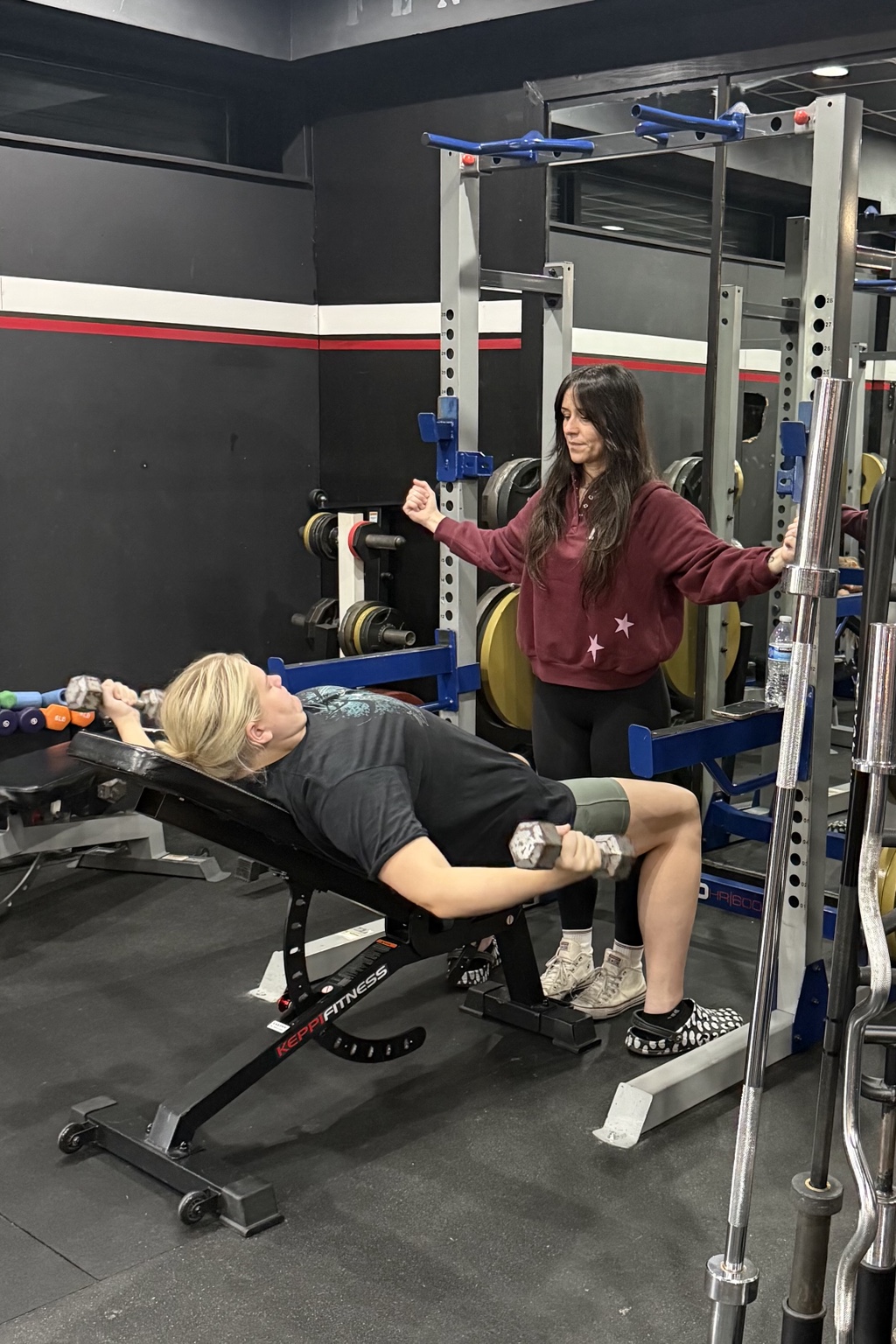 A trainer guiding a member through an incline dumbbell exercise.